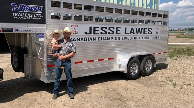 Jesse Lawes and his child in front of his livestock trailer