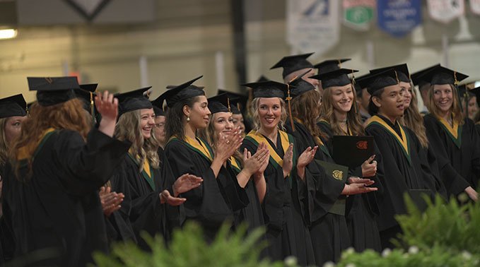 A group of graduating students take part in a stand ovation.