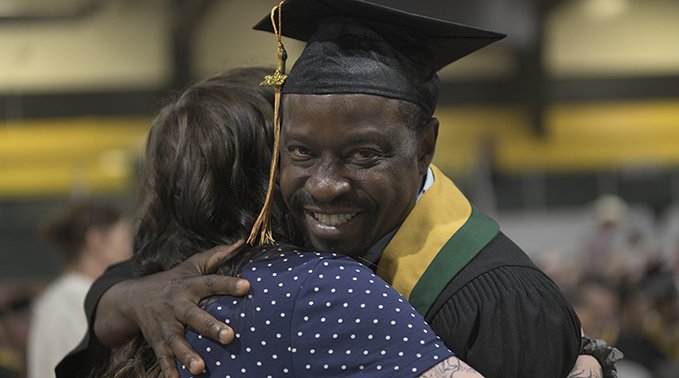 A Lakeland College graduate smiles as he hugs a faculty member.