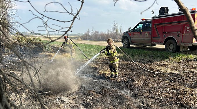 A Lakeland College emergency services technology student exstinguishes hot spots following a fire in Entwistle, Alta.