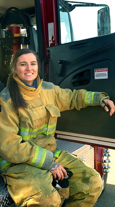 Larisa Staub sits along the side of a fire truck.