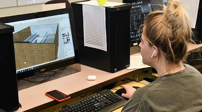 An interior design technology student works on a rendering during class.