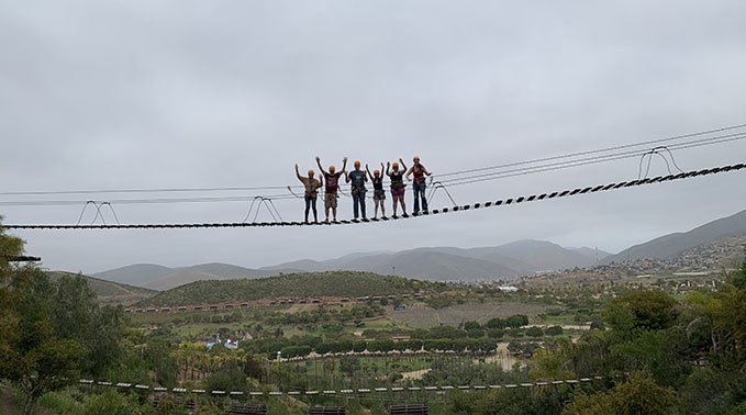 From a distance, a group of people stand on a suspended bridge in Ensenada Mexico