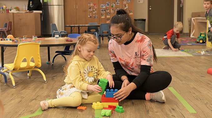 A human services student plays with building blocks with a child during the award-winning student-run play program.