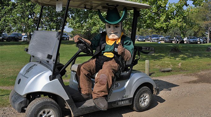 Sitting in a golf cart at the 2023 Rustlers Golf Tournament, the Rustlers's mascot Rowdy gives a thumbs up to Next Gen Automation for their support.