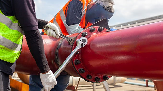 Steamfitter-pipefitters work up close tightening bolts