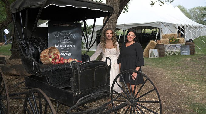 Two students stand in front of the event tent at the welcome sign of Feast on the Farm 2023.