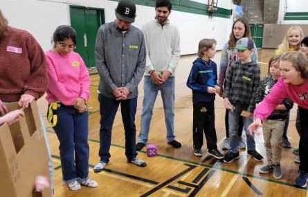 Rolling dice and throwing bean bags in a gym game.