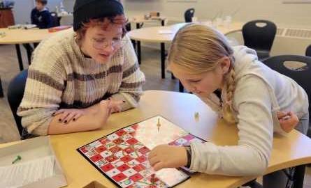 Child and youth care counsellor student plays Snakes'n'Ladders with a girl.