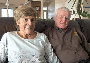 Rita and Armin Mueller sitting on a couch in their home