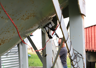 Photo of man installing sensors on Grain Drying bin