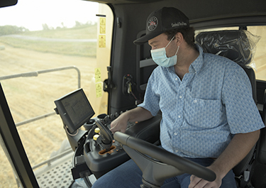 A student operates a New Holland combine featuring IntelliSense combine automation technology.