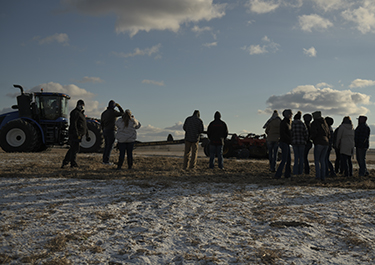 Students watch as the tillage equipment works pea straw into the frozen ground.