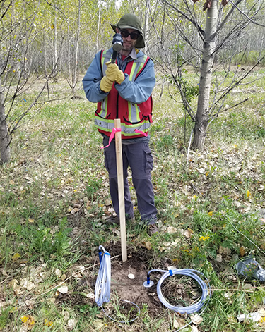 James hammering a stake in a forest