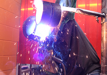Tiegan Larouche, third year welding apprentice, in a welding booth.