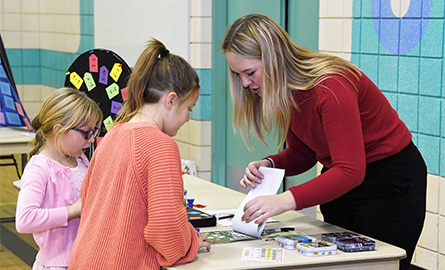 Student working with elementary students at math fair