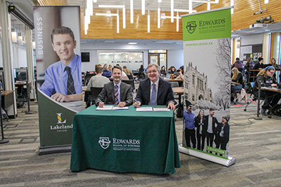 Brad Onofrychuk, dean of business and energy at Lakeland (left), signs the Memorandum of Understanding with Keith Willoughby, dean of the Edwards School of Business (right).