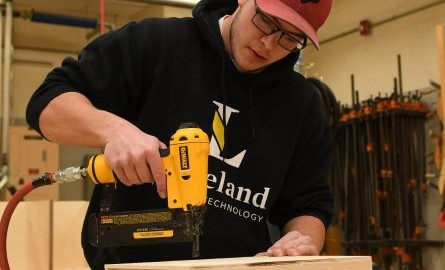 Student operating a drill in the workshop