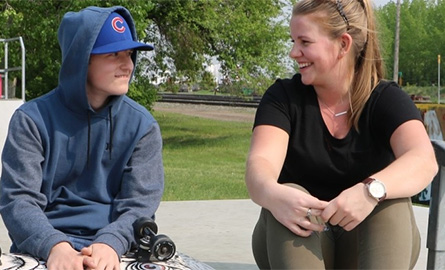Child and student talk together at a skate park