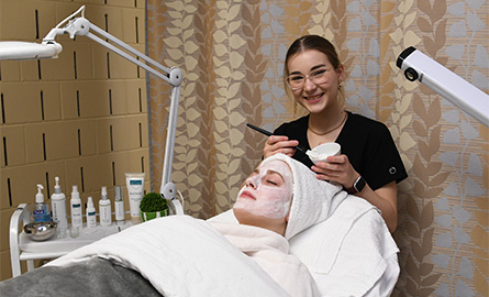 Student performing facial procedure on client in spa