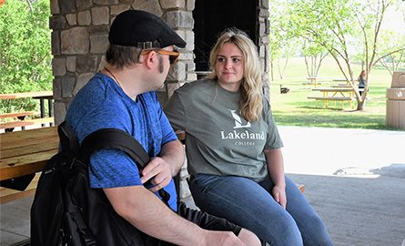 Student listening with a client in a park
