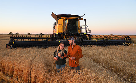 Students standing in a field with a combine behind them