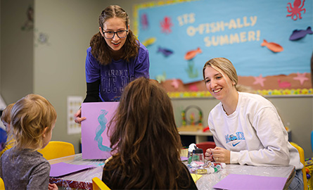 Students playing with children in a classroom