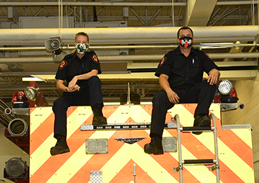 Candice Ives and Braden Olynick sit on top of one of the Emergency Training Centre's firetrucks.