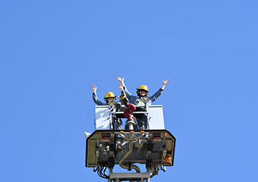 A couple of students wave from above during a ladder exercise.