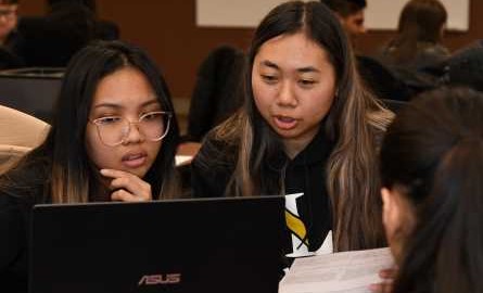 2 students in front of computer help someone with their taxes