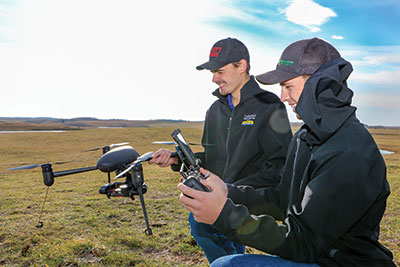 Two agricultural sciences students operate a drone.