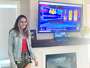 emmaleigh ayotte beside a screen announcing she'd won bronze