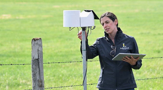 A Lakeland College staff member holds a tabelet while investigating a weather sensor