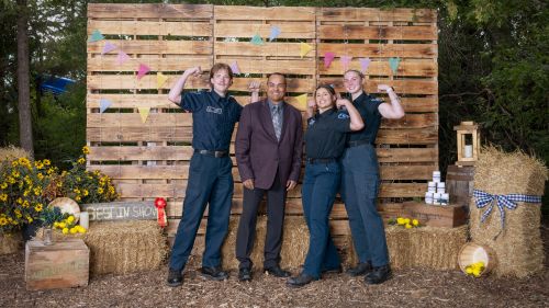 A group of students in uniform with an event guest.