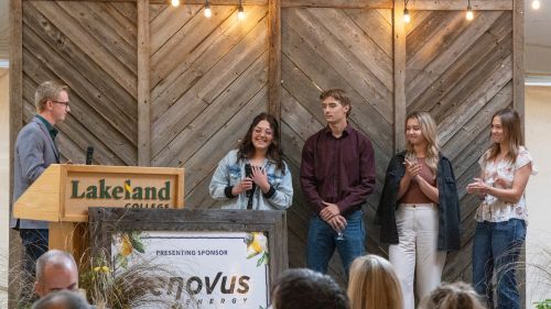 A Lakeland College alumnus talks from the podium with a group of students.