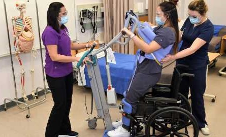 2 health care aide students learn lift assist