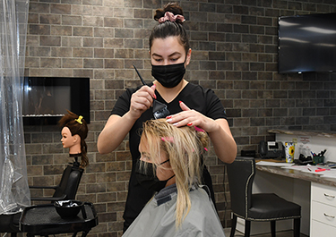 A hairstyling student applies colour to her clients hair.
