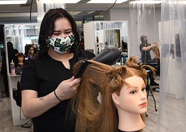 Photo of Lakeland College student Zoe Quinny practices hairstyling on a model.