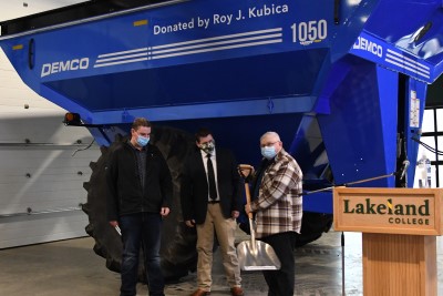 Roy Kubica (right) hands over a ceremonial grain shovel to Tyson Krpan (left) while Geoff Brown (centre), dean of agricultural sciences, looks on during the unveiling of the new grain cart.