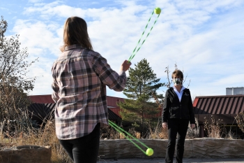 A student works with poi balls and Karen Harris