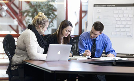 Three people working together and using a laptop