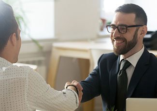 smiling man in business suit greets a customer over the counter