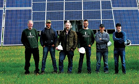 Sustainable energy technology students standing in field in front of solar panels