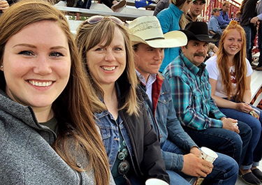 All 5 members of the Hlus family in the grandstand at an outdoor rodeo.