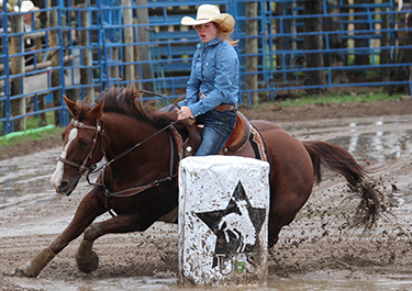 Quinn Hlus on a horse, racing around a barrel.