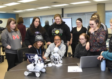 UT students gather around Tech Force members to watch them code a robot to dance.
