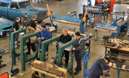 overview of vehicle restoration lab with men working in various stations