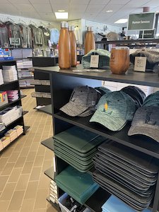hats and waterbottles on a shelf with a view of a college bookstore in the background