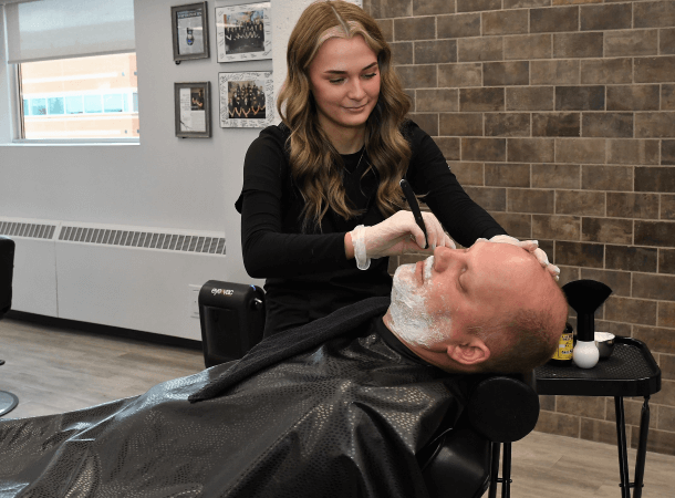 Student shaving a client's beard