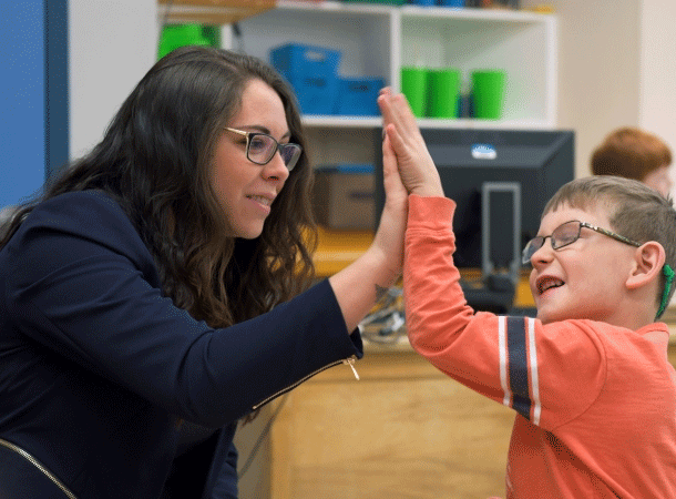 Educational Assistant high-fives a student